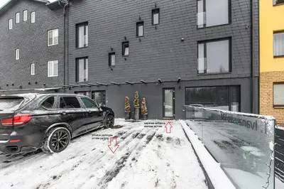 a car parked in front of a building in the snow at Botanical Garden Loft in Kaunas