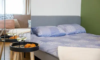 a room with a bed and two glasses of wine at Groundfloor Apartment on the Green Hill in Kaunas