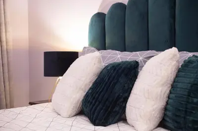 four pillows on a bed with a green headboard at Siauliai Apartments - Lieporiu in Šiauliai