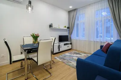 a living room with a table and a blue couch at Moder Chic Apartment in Center-PRIME RENTALS in Kaunas