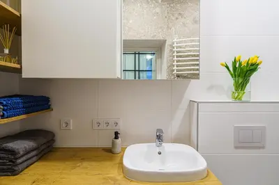 a white bathroom with a sink and a mirror at Moder Chic Apartment in Center-PRIME RENTALS in Kaunas