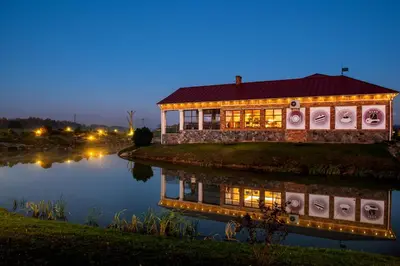 a house with lights on the water at night at Motelis SMAKŲ SMAKAS in Šiauliai
