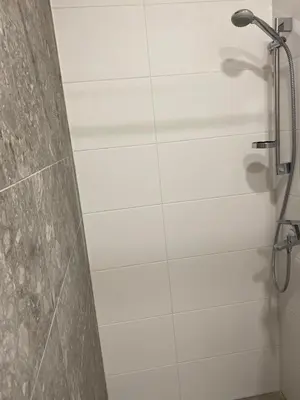 a shower in a bathroom with a white tile wall at Modern Rustic in Center-PRIME RENTALS in Kaunas