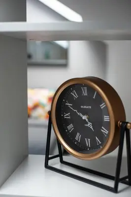 a clock sitting on a stand in a room at E.M. Studio In City Center in Kaunas