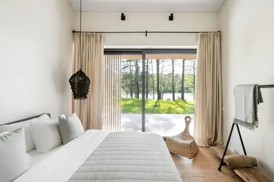 a bedroom with a bed and a large window at Villa The Lake in Mindūnai