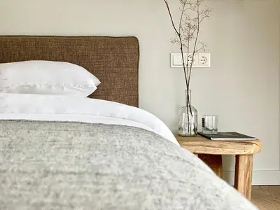 a bedroom with a bed and a table with a vase at Villa The Lake in Mindūnai
