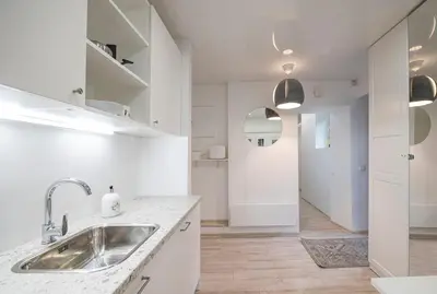 a white kitchen with a sink and a hallway at Kepezinski Centre Apartments in Kaunas
