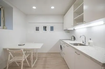 a white kitchen with a sink and a table at Kepezinski Centre Apartments in Kaunas