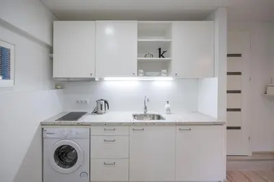 a white kitchen with a sink and a washing machine at Kepezinski Centre Apartments in Kaunas