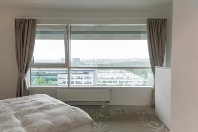 a bedroom with a large window with a view of a city at VilniausPanorama in Vilnius