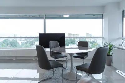 a table and chairs in a room with large windows at VilniausPanorama in Vilnius