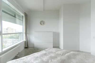 a white bedroom with a bed and a window at VilniausPanorama in Vilnius