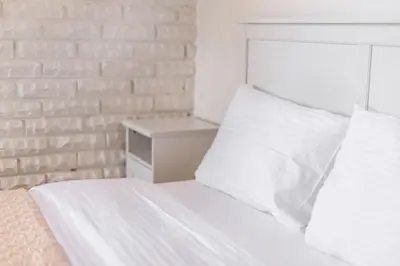 a bed with white sheets and a brick wall at Castle View Apartment by Reside Baltic in Vilnius