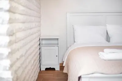 a white bedroom with a bed and a night stand at Castle View Apartment by Reside Baltic in Vilnius