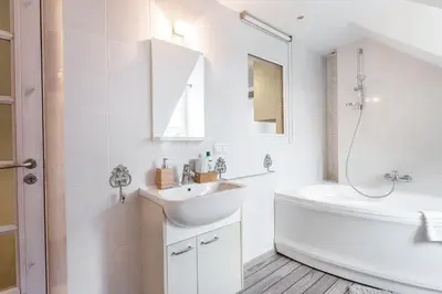 a white bathroom with a sink and a tub and a toilet at Castle View Apartment by Reside Baltic in Vilnius