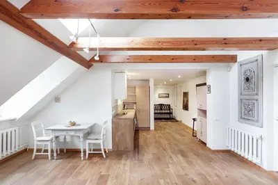 a kitchen and dining room with white walls and wooden beams at Castle View Apartment by Reside Baltic in Vilnius