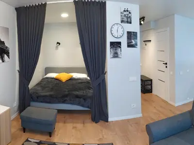 a bedroom with a bed and a clock on a wall at Studija Alytuje in Alytus