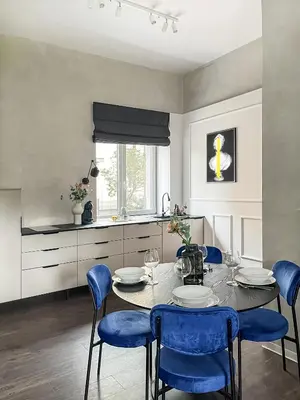 a dining room with a table and blue chairs at Kamurke - Apartamentai in Šiauliai
