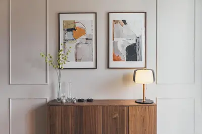 a table with a lamp and two pictures on a wall at Lindens apartments with AC and view to central square in Panevėžys