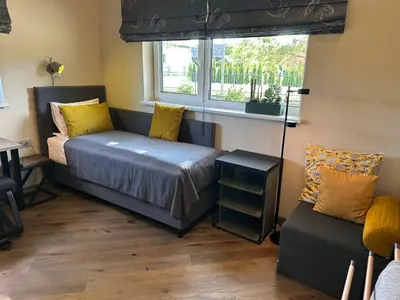 a bedroom with a bed and a chair and a window at MĖTA in Birštonas