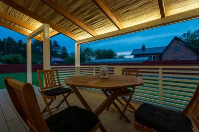 a deck with a wooden table and chairs at Jaukus svečių namelis in Druskininkai