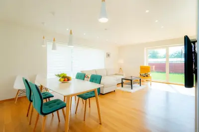 a living room with a table and green chairs at Jaukus svečių namelis in Druskininkai