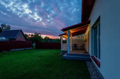 a house with a deck with a sunset in the background at Jaukus svečių namelis in Druskininkai