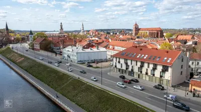 a city with a river and a street with cars at Kaunas Old Town apartment with underground parking in Kaunas