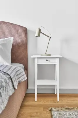 a white bedside table with a lamp next to a bed at New and Lovely Apartament in Vilnius City Centre in Vilnius