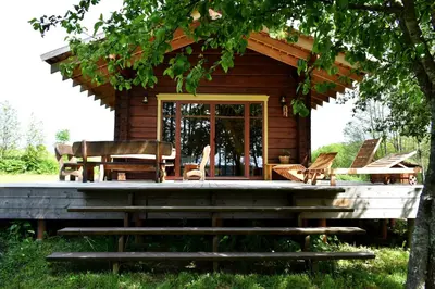 a log cabin with a porch and a table and chairs at Kaimukas - namelis prie ežero keturiems in Dvarčėnai