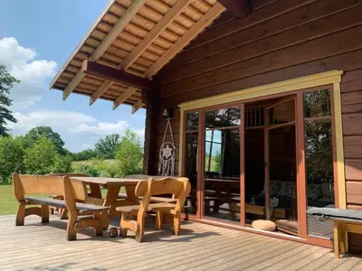 a wooden deck with a table and chairs on it at Kaimukas - namelis prie ežero keturiems in Dvarčėnai