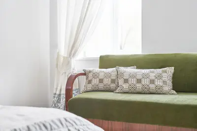 a green chair with pillows in front of a window at Bright and Warm Apartment, Vilnius City Centre in Vilnius