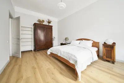a white bedroom with a bed and a wooden floor at Bright and Warm Apartment, Vilnius City Centre in Vilnius