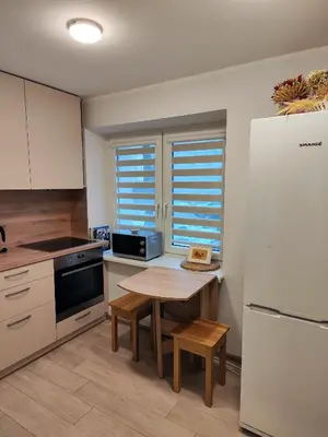 a kitchen with a table and a white refrigerator at Adelės apartamentai in Druskininkai