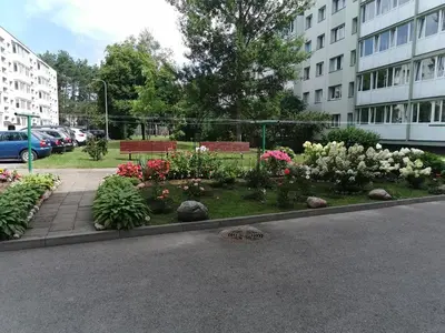 a garden with benches and flowers in a city at Adelės apartamentai in Druskininkai