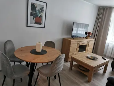 a living room with a table and chairs and a television at Adelės apartamentai in Druskininkai