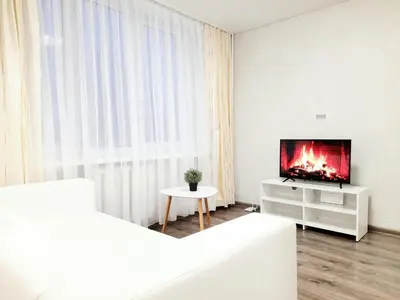 a white living room with a tv and a table at M&M Apartment II SELF CHECK-IN in Panevėžys
