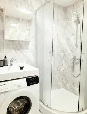 a washing machine in a bathroom with a shower at M&M Apartment II SELF CHECK-IN in Panevėžys