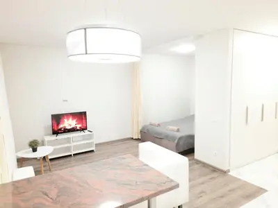 a white living room with a table and a tv at M&M Apartment II SELF CHECK-IN in Panevėžys