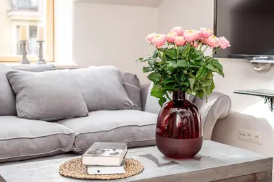 a red vase with pink roses on a coffee table at Luxury Gaono in Old Town in Vilnius