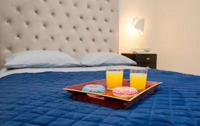 a tray of donuts and two glasses of orange juice on a bed at Luxurious Blue&Yellow Apartment in Kaunas Center in Kaunas