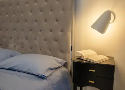 a bed with a lamp and a book on a night stand at Luxurious Blue&Yellow Apartment in Kaunas Center in Kaunas