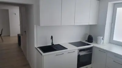 a white kitchen with a sink and a stove at City center apartment in Alytus