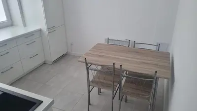a kitchen with a wooden table and four chairs at City center apartment in Alytus