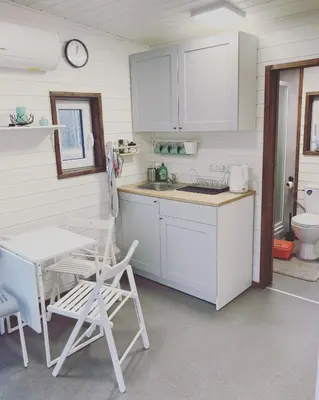 a kitchen with white cabinets and a table and a sink at Riešutynė in Gražuliai