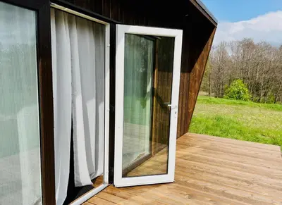 an open sliding glass door on a wooden deck at Riešutynė in Gražuliai