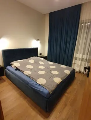 a bed sitting in a room with a blue curtain at Žvėrynas Workation apartments in Vilnius