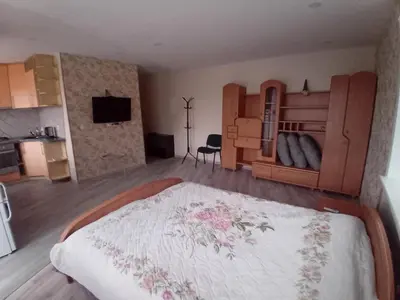 a bedroom with a large bed and a kitchen at Butas miesto centre - bulvare in Šiauliai