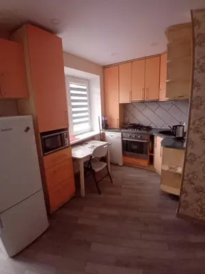 a kitchen with wooden cabinets and a table in it at Butas miesto centre - bulvare in Šiauliai
