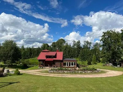 a log cabin with a red roof on a grass field at Laukupės sodyba in Rokiškis